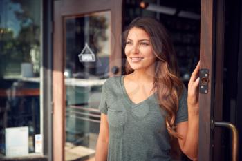 Female Owner Of Start Up Coffee Shop Or Restaurant Standing In Doorway