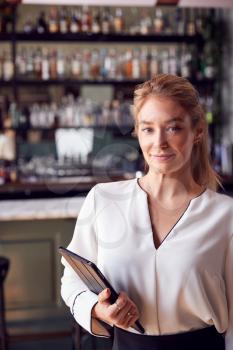 Portrait Of Confident Female Owner Of Restaurant Bar Standing By Counter Holding Digital Tablet