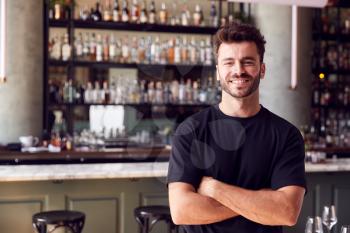 Portrait Of Confident Male Owner Of Restaurant Bar Standing By Counter