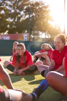 Womens Football Team Stretching Whilst Training For Soccer Match On Outdoor Astro Turf Pitch