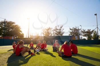 Womens Football Team Stretching Whilst Training For Soccer Match On Outdoor Astro Turf Pitch