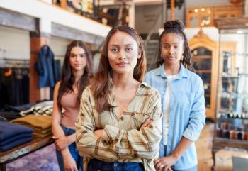Portrait Of Multi-Cultural Female Sales Team In Fashion Store Standing In Front Of Clothing Display