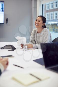 Laughing Asian Businesswoman Sitting At Table In Office  Meeting Room