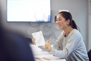 Asian Fashion Designer Sitting At Table In Office  Meeting Room Presenting Designs