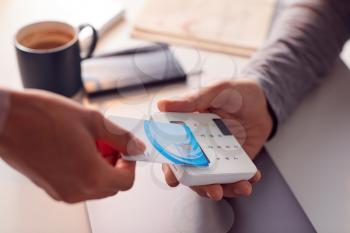 Woman Making Contactless Payment Using Credit Card To Man Holding Card Reader