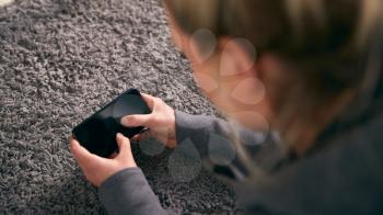 Overhead Shot Of Woman Looking At Screen With Copy Space On Mobile Phone Lying On Carpet