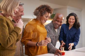 Group Of Mature Friends Meeting At Home To Celebrate Womans Birthday With Cake