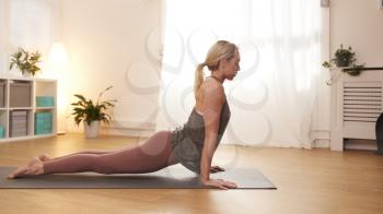 Woman In Yoga Studio Standing On Exercise Mat And Stretching