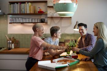 Group Of Friends Celebrating With Beers Meeting At Home And Eating Takeaway Pizza