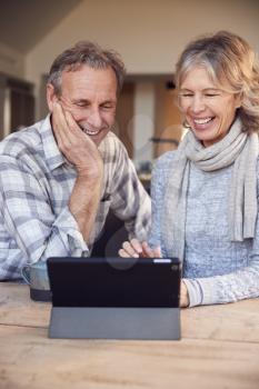 Retired Senior Couple At Home Buying Products Or Services Online Using Digital Tablet