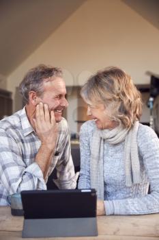 Retired Senior Couple At Home Buying Products Or Services Online Using Digital Tablet