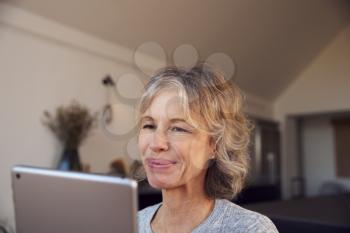 Close Up Of Smiling Mature Woman At Home Using Digital Tablet