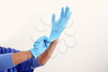 Close Up Of Female Nurse Wearing Scrubs Putting On Sterile PPE Gloves