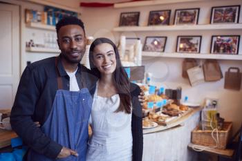 Portrait Of Smiling Couple Running Coffee Shop Together Standing Behind Counter