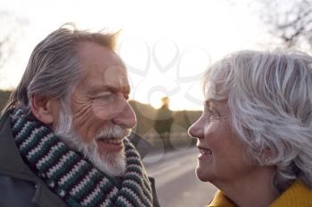 Portrait Of Loving Senior Couple Enjoying Autumn Or Winter Walk Along Country Road Together