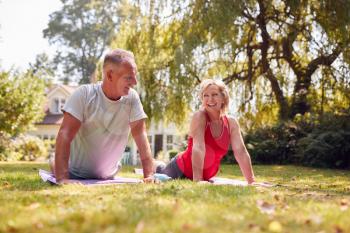 Senior Couple At Home In Garden Wearing Fitness Clothing Enjoying Outdoor Yoga Class