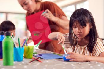 Asian Mother With Children Having Fun With Children Doing Craft On Table At Home