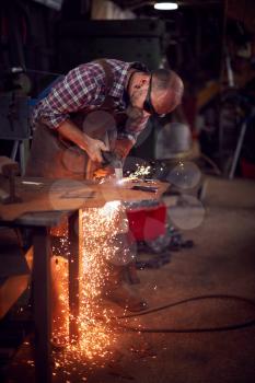 Male Blacksmith Using Plasma Cutter To Cut Shape From Sheet Metal In Forge