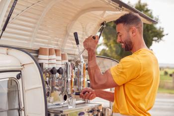 Man Running Independent Mobile Coffee Shop Preparing Drink Standing Outdoors Next To Van