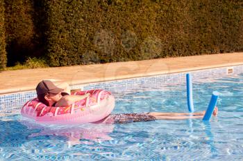 Young Man Relaxing On Summer Vacation Floating In Swimming Pool In Inflatable Ring