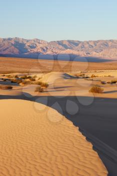 The famous Death Valley in California. Sand dunes and ancient mountains. Pink sunrise