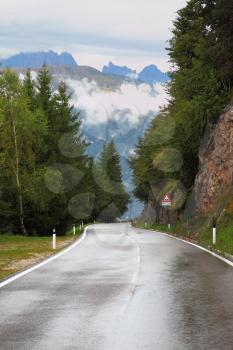 Wet shiny road in the Swiss Alps. Cold autumn day
