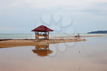 Sandy beach on Koh Samui. The red beach wooden arbor is picturesquely reflected in water
