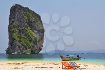 Charming resort landscape. White sand, island near to coast and two cozy beach chaise lounges. Thailand