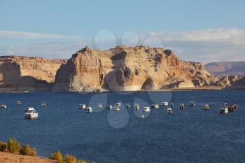 Flotilla of elegant white yachts on Lake Powell. Small waves on the lake from the evening breeze