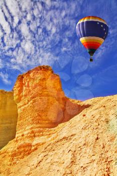The bright decorative balloon flies above stone desert 