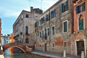 The small graceful bridge through the Venetian channel. Narrow street to Venice, a sunny day
