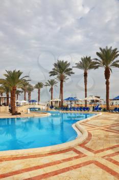 Winter in the Dead Sea. The picturesque swimming pool, palm trees and beach umbrellas