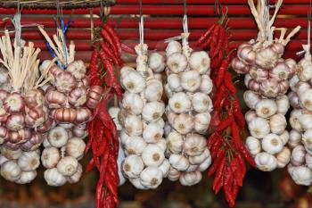 Bundles of garlic and bundles of cayenne pepper hanging on  wicker fence of the southern market




