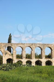 Perfectly kept Roman antique aqueduct on a green grassy meadow in the north of Israel