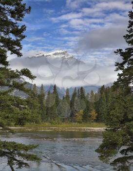 
The mountain river with the transparent water and snow-covered mountain  on a background
