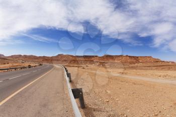Highway in orange stone desert. Israel, midday
