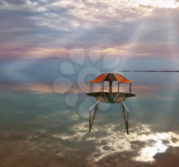Incredible optical effects at the Dead Sea. The picturesque beach arbor for swimmers is reflected in a smooth sea surface.