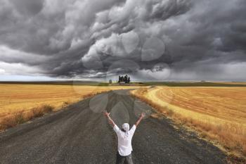 The enthusiastic tourist welcomes thunderstorm above Montana. Fields after a harvest and road
