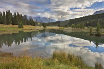  Lake in mountains surrounded by a wood and the cloudy sky above it