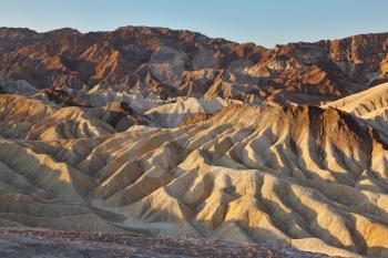The famous section of Death Valley in California - Zabriskie Point. Picturesque hills of pink, yellow and chocolate hues at sunset
