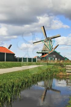 The village - an ethnographic museum in Holland. The picturesque windmill and a barn is reflected in smooth water of the channel