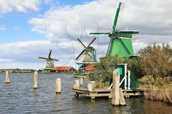 The village - an ethnographic museum in Holland. Three windmills and berthing columns on the bank of the channel