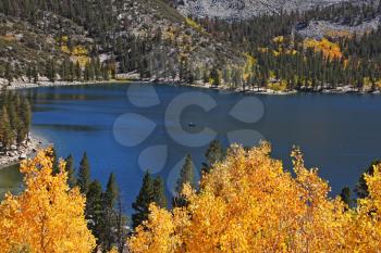 Magnificent mountain lake with bright blue water, surrounded by yellow and orange trees