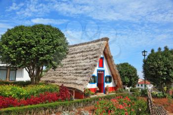 Old house-museum of the first settlers on the island of Madeira. Charming white cottage with a thatched roof and gable small garden with flowers