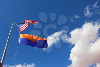 Flags of the United States and the Navajo Reservation are flying against the clouds