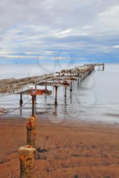 Old dilapidated pier in the Strait of Magellan. Corroded bearings and collapsed wooden flooring