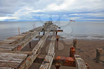 Old dilapidated pier in the Strait of Magellan. Corroded bearings and collapsed wooden flooring