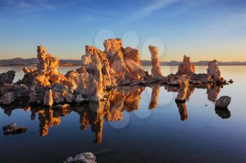 Orange sunset on Mono Lake. Outliers - bizarre calcareous tufa formation  reflected in the smooth water.