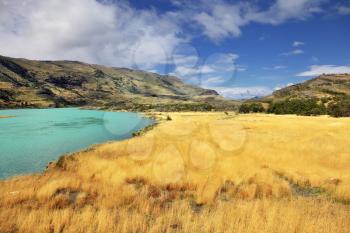 National Park Torres del Paine in southern Chile, in Patagonia. The sharp strong wind bends the yellowed grass. Emerald Lake is covered by waves