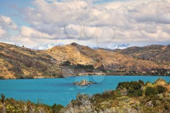 Azure water of Lake Pehoe between green and yellow hilly coast.  National Park Chile - Torres del Paine